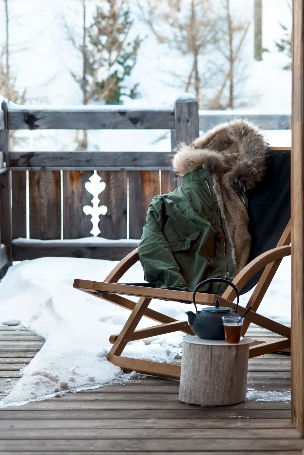 Chaise longue en bois et plaid sur la terrasse enneigée du chalet